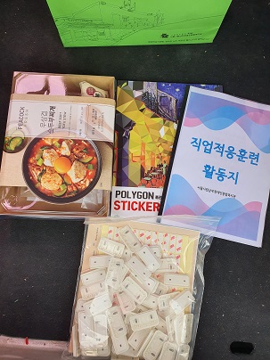 활동지와 메모홀더 작업물품, 밀키트, 스티커아트북이 책상위에 올려져있다.