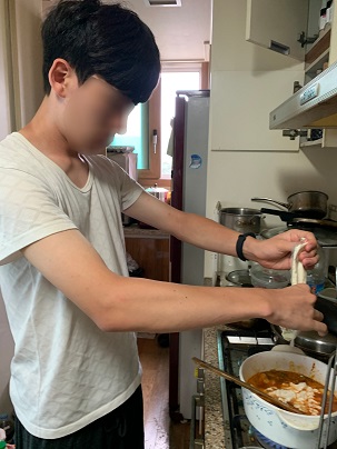 남자훈련생이 국물이 끓고있는 냄비에 순두부를 넣고있다.