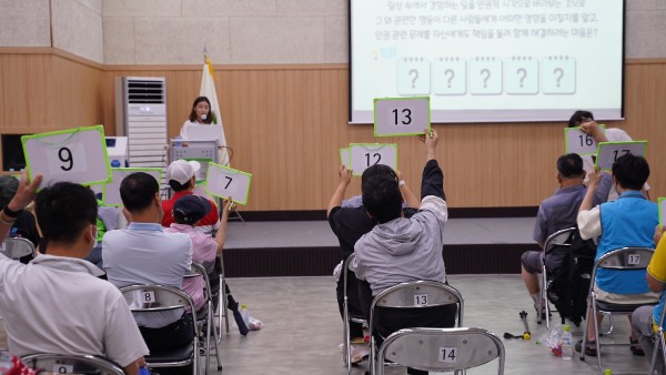 퀴즈대회 정답을 들고 있는 참여자들의 뒷모습과 PPT화면
