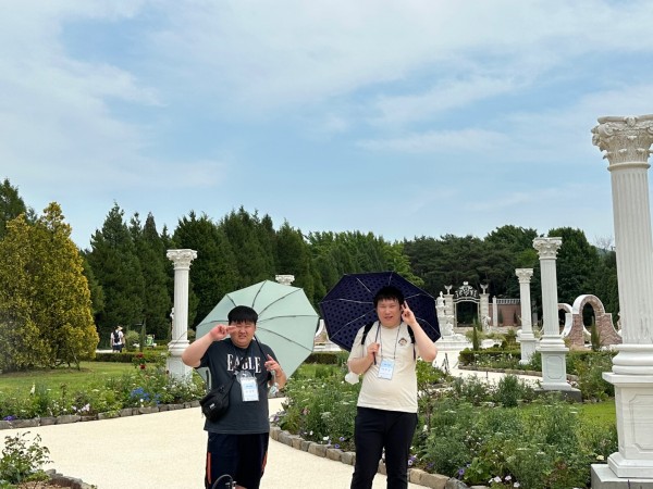 2명의  남자 참여자가 날씨가 더워서 양산을 쓰고 있는 모습