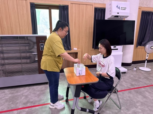 참여자가 완료한 투표용지를 투표함에 넣는 모습