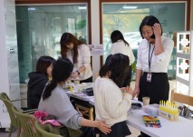 강당 앞에 공간에 설치된 스마트팜 기계 앞에서 스마트팜과 관련된 부스를 열어 모종심기 체험에 참여하고 있는 참여자의 모습
