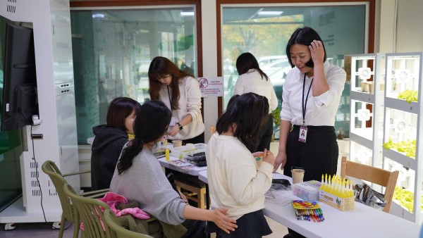 강당 앞에 공간에 설치된 스마트팜 기계 앞에서 스마트팜과 관련된 부스를 열어 모종심기 체험에 참여하고 있는 참여자의 모습