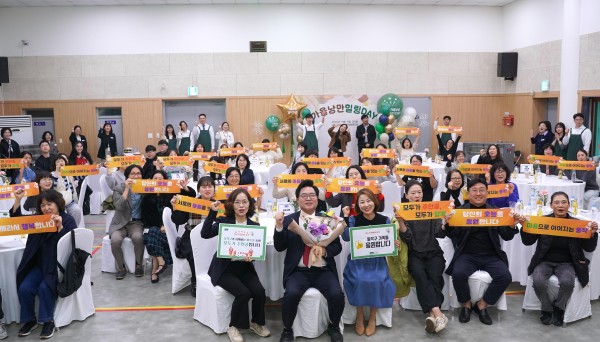 행사에 참여한 인원들이 강당에 앉아 슬로건을 들고 단체사진을 찍는 모습