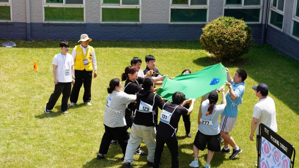 서울시립남부장애인종합복지관 중정에서 제기와 보자기를 이용하여 떨어트리지 않는 단체게임을 하는 사진