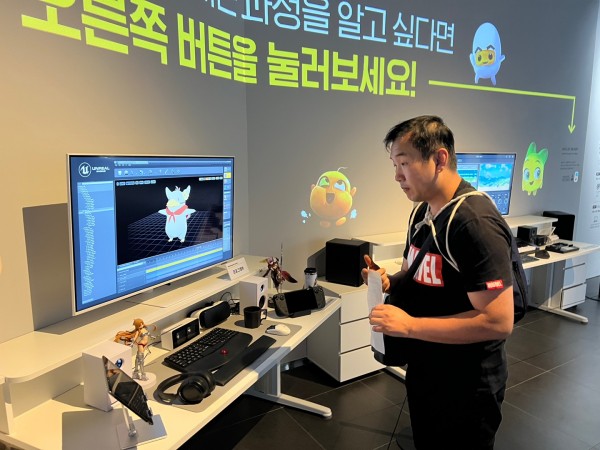 남성 동아리원 1명이 손에 종이를 들고 박물관 내 컴퓨터 화면을 바라보고 있습니다.