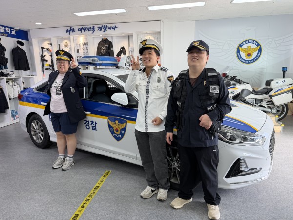 제복을 입고 경찰차 앞에서 사진을 찍는 모습