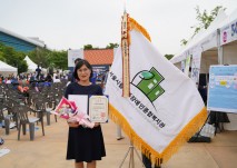 대리수상자 송주혜 사무국장이 표창장을  들고 기념사진 촬영을 하고 있다.