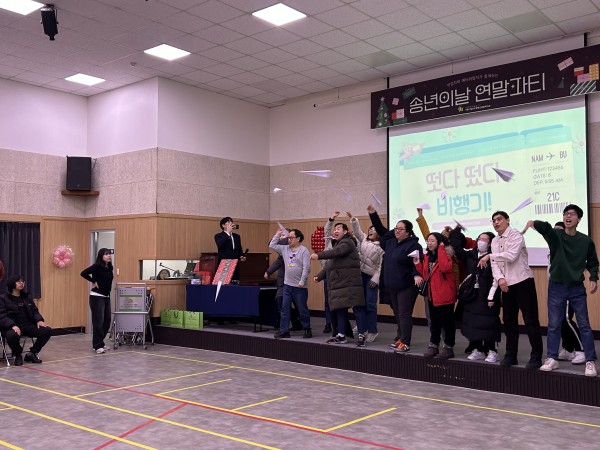송년회 참여자들이 단체로 종이비행기를 날리고 있다